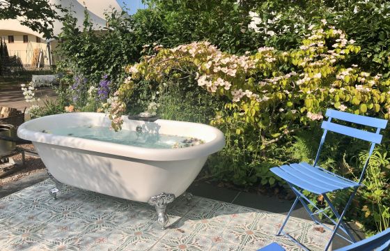 white bath tub in garden surrounded by flowering cornus