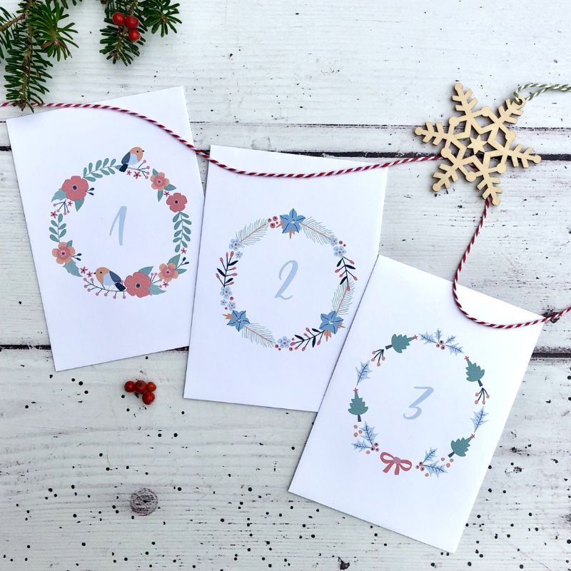 advent calendar envelopes with wreath designs and bakers twine and wooden snowflake