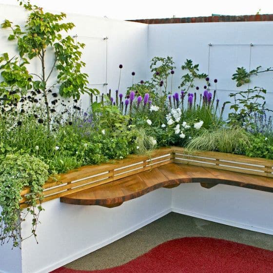 raised bed planted with flowers and shrubs against a white wall ideal new build garden idea
