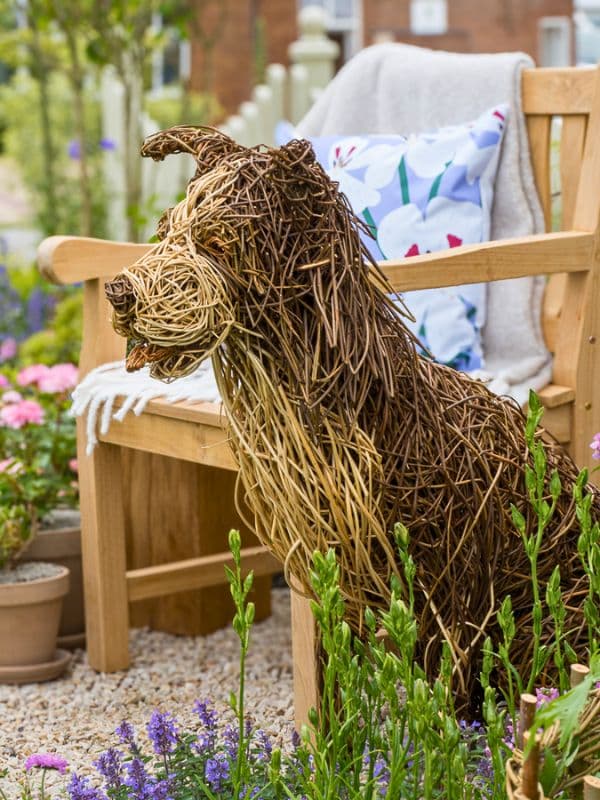 willow dog sculpture sheep dog sat down next to garden chair